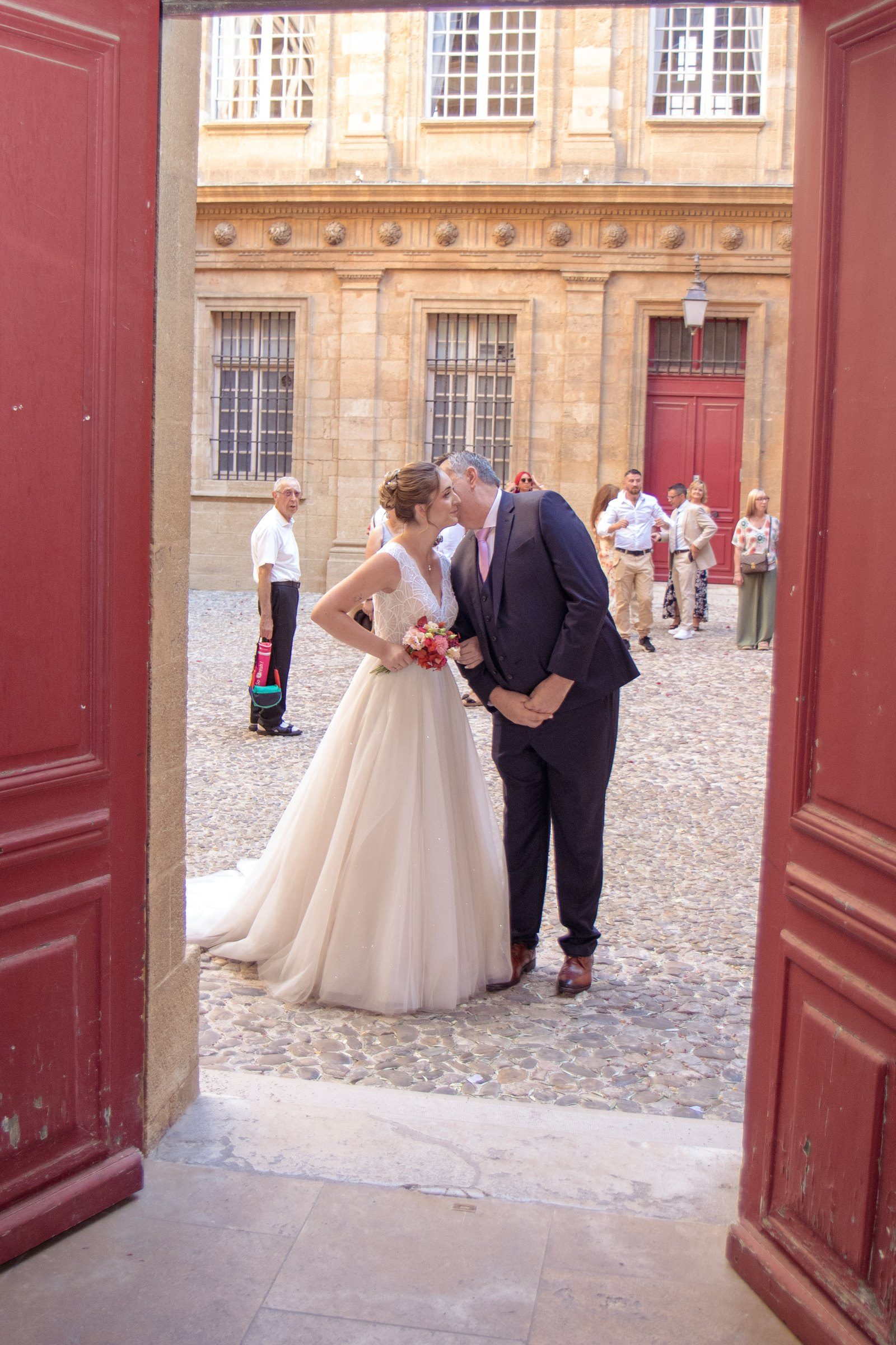 Les mariés vus depuis la porte de la mairie, dans la cour pavée