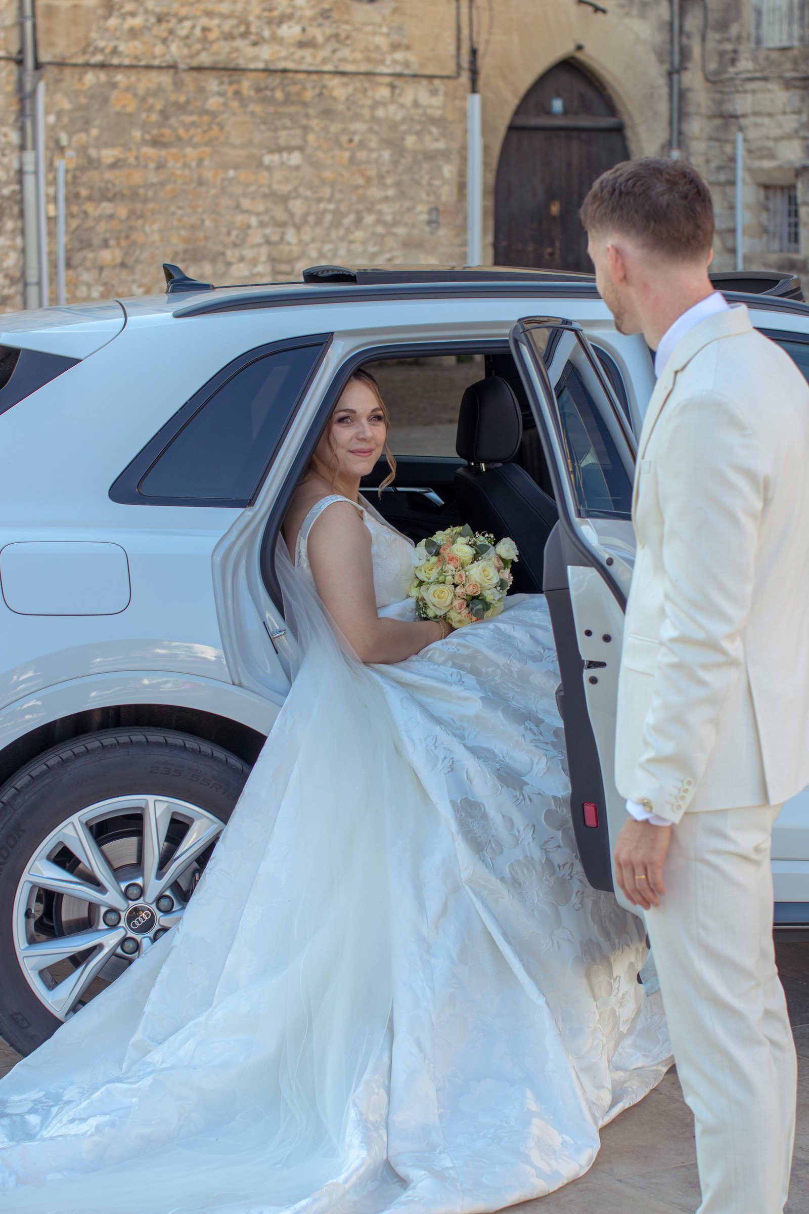 Le marié ouvre la portière à la mariée à son arrivée