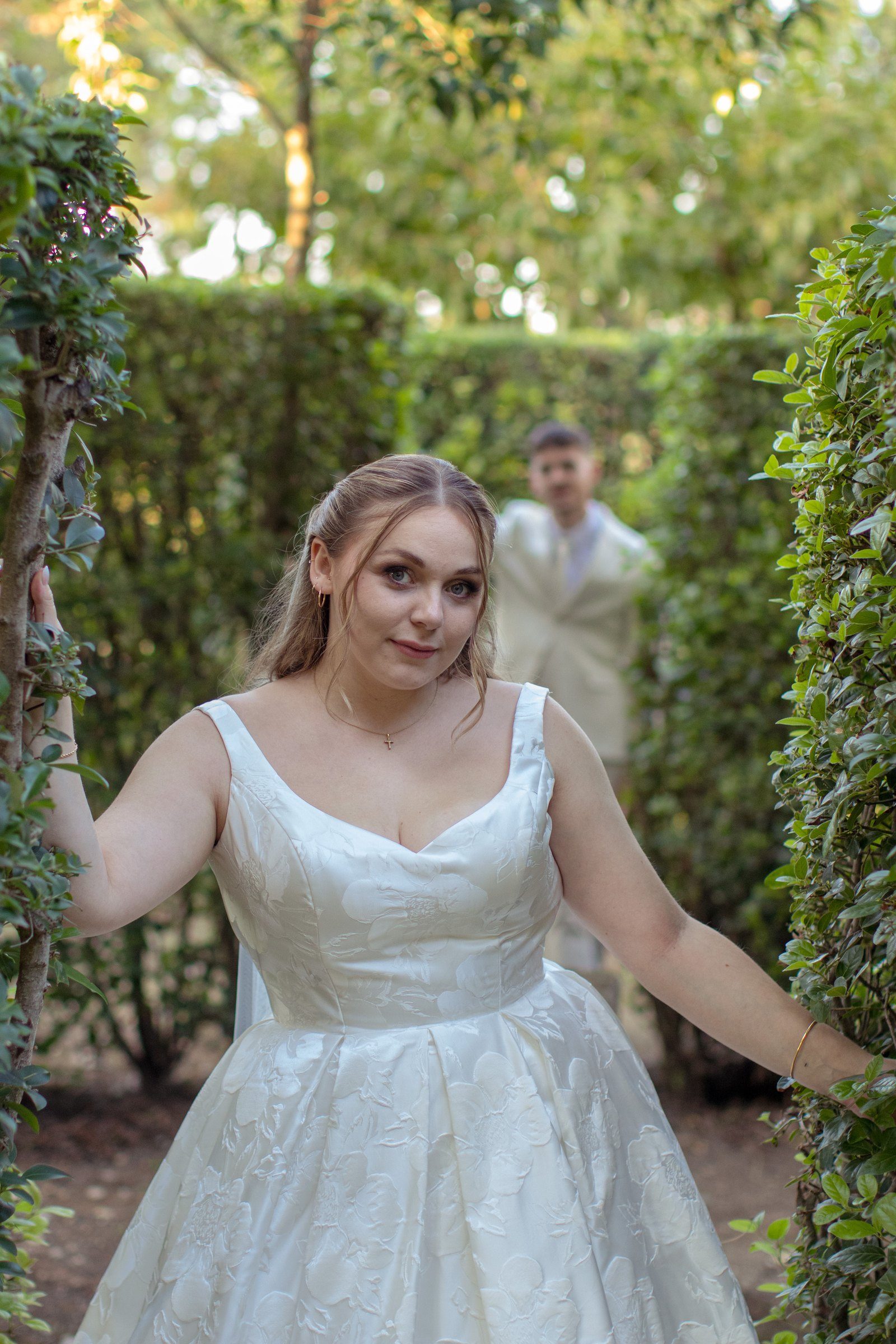 La mariée sourit au milieu des haies du jardin