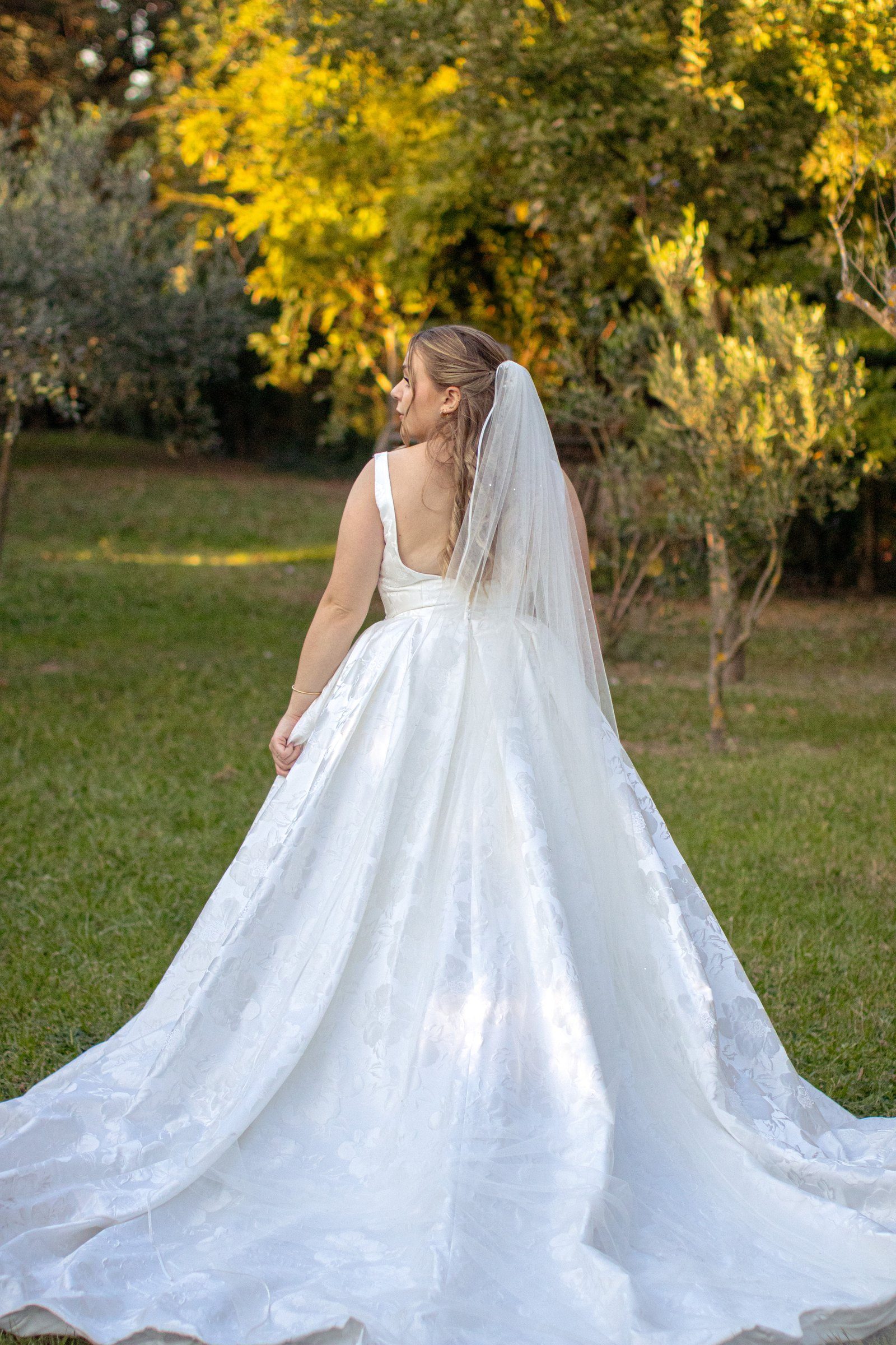 La mariée de dos, sa longue traîne étalée sur l'herbe