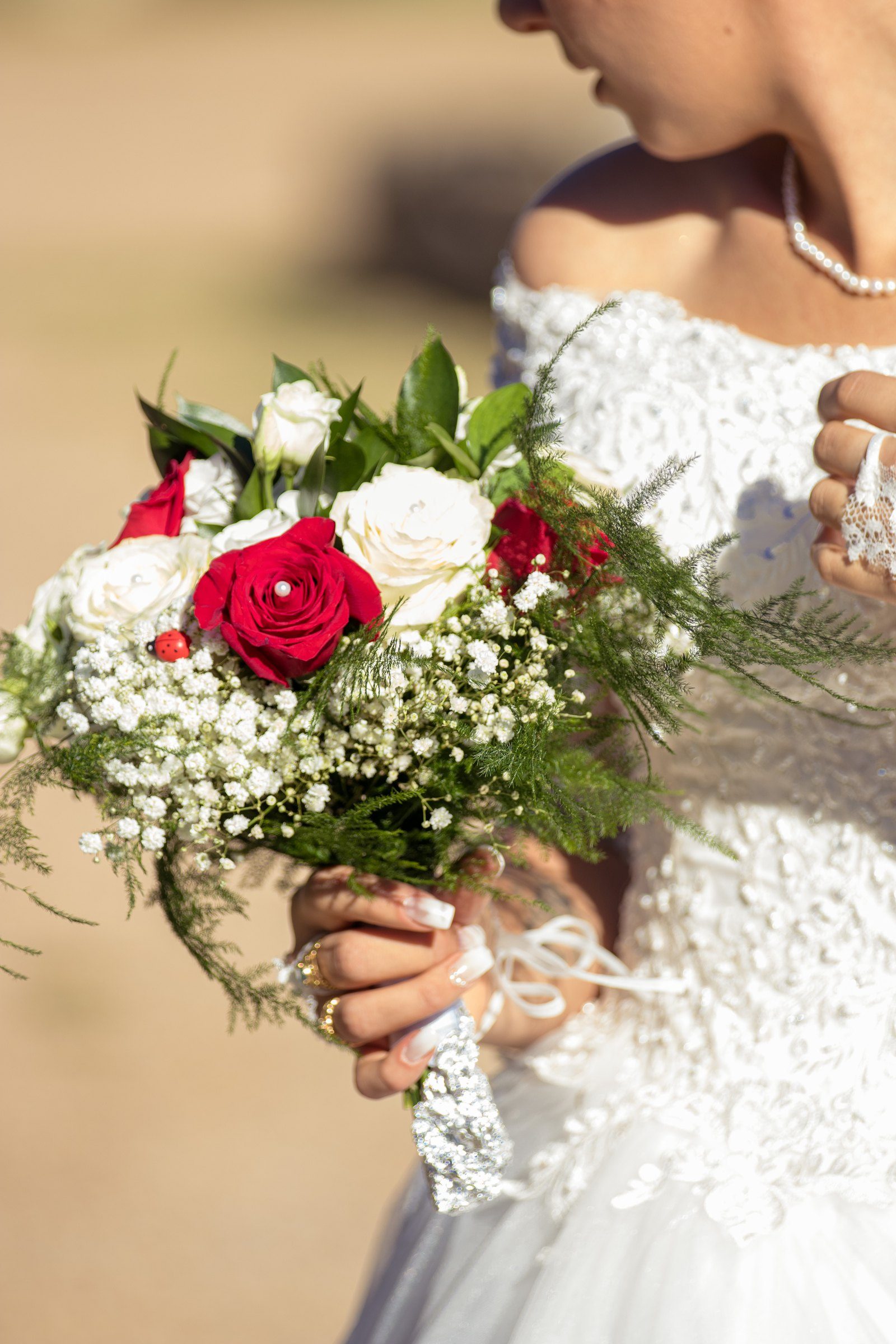 Bouquet de roses rouges et de gypsophile dans les mains de la mariée
