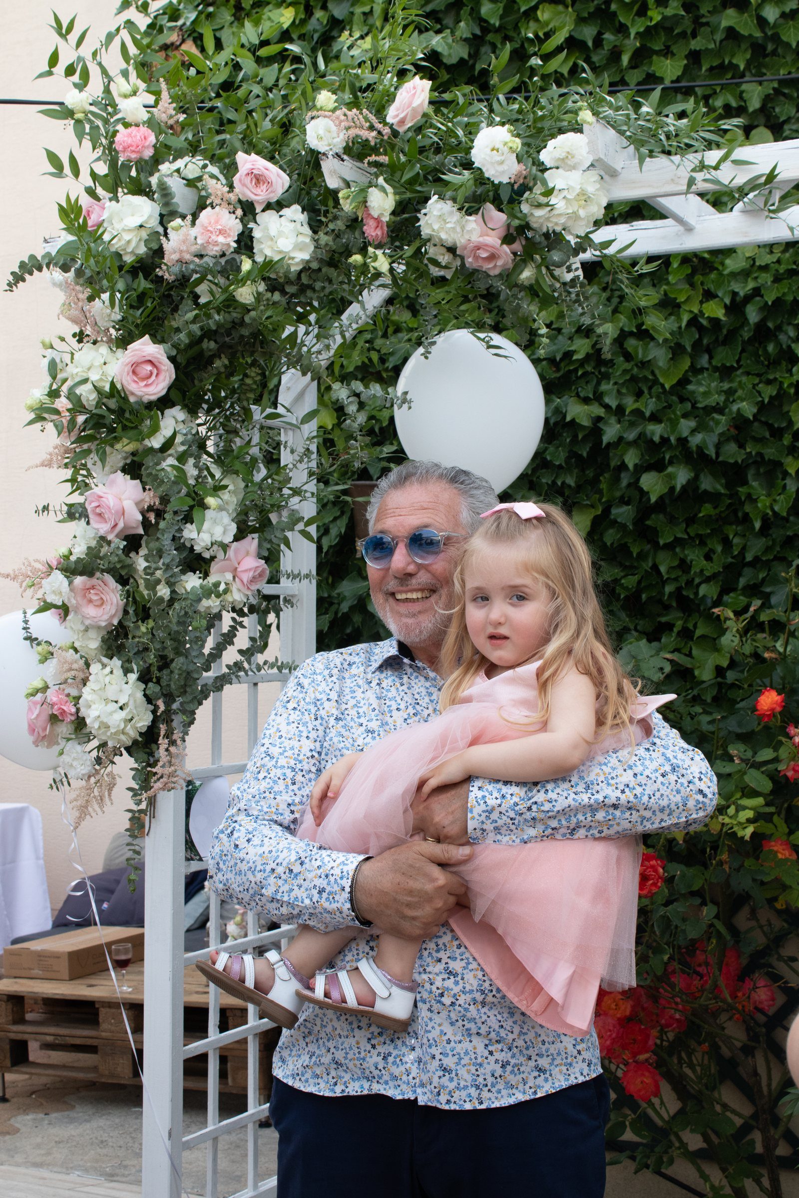 Un grand-père et sa petite-fille sous l'arche fleurie