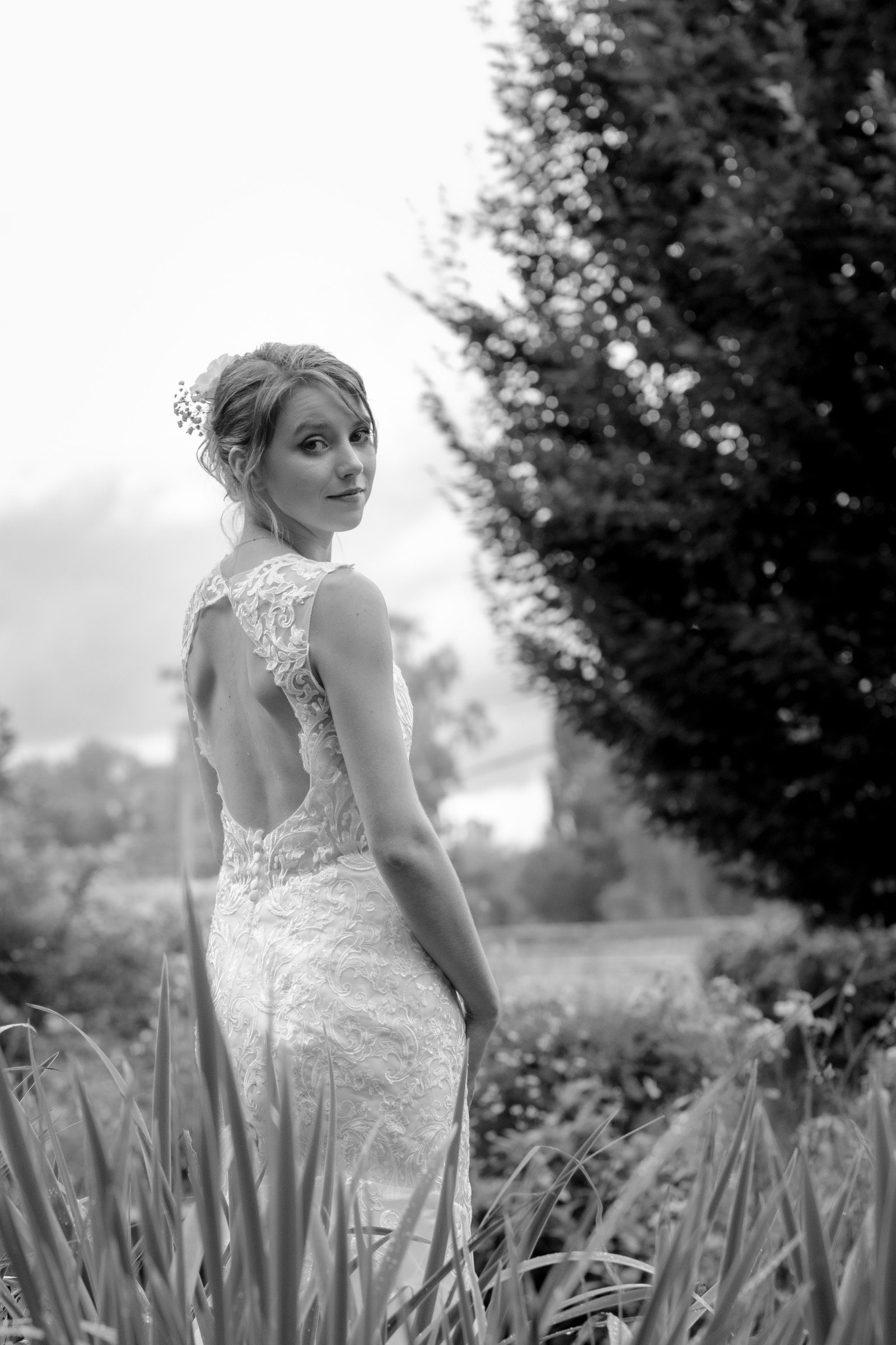 La mariée de dos regarde par-dessus son épaule, en noir et blanc