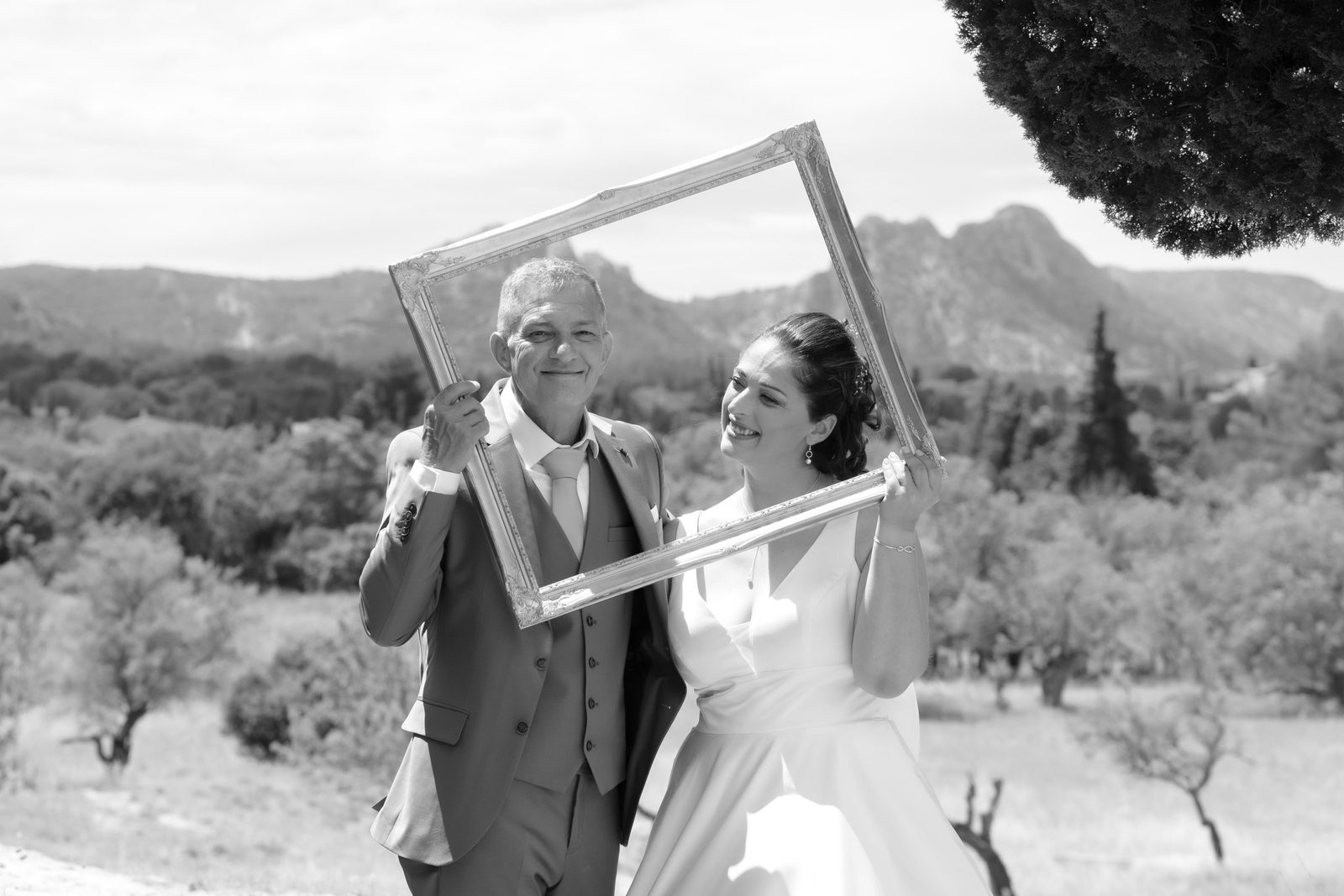 Les mariés avec un cadre face aux Alpilles, en noir et blanc