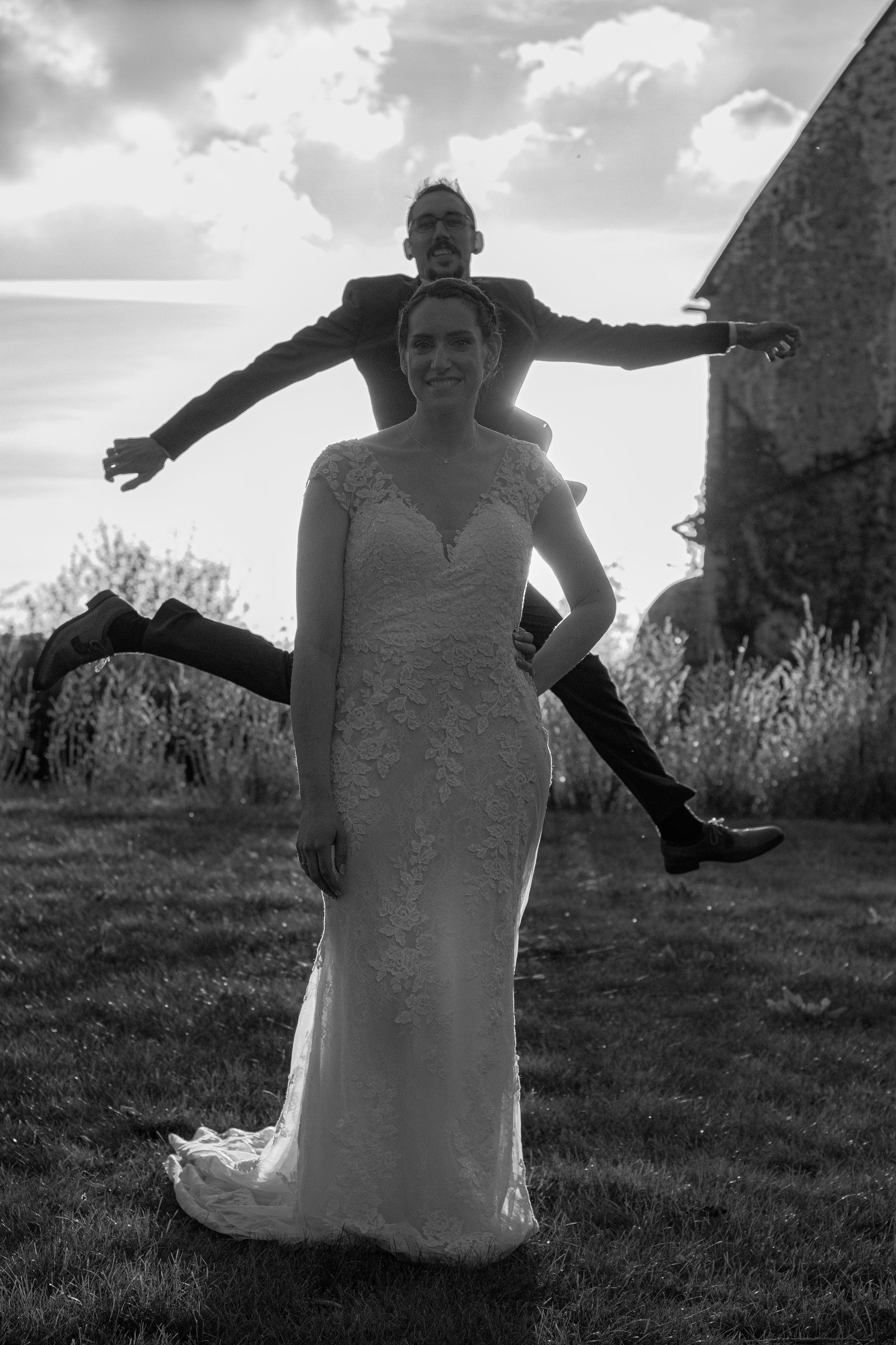 Le marié saute derrière la mariée, en noir et blanc