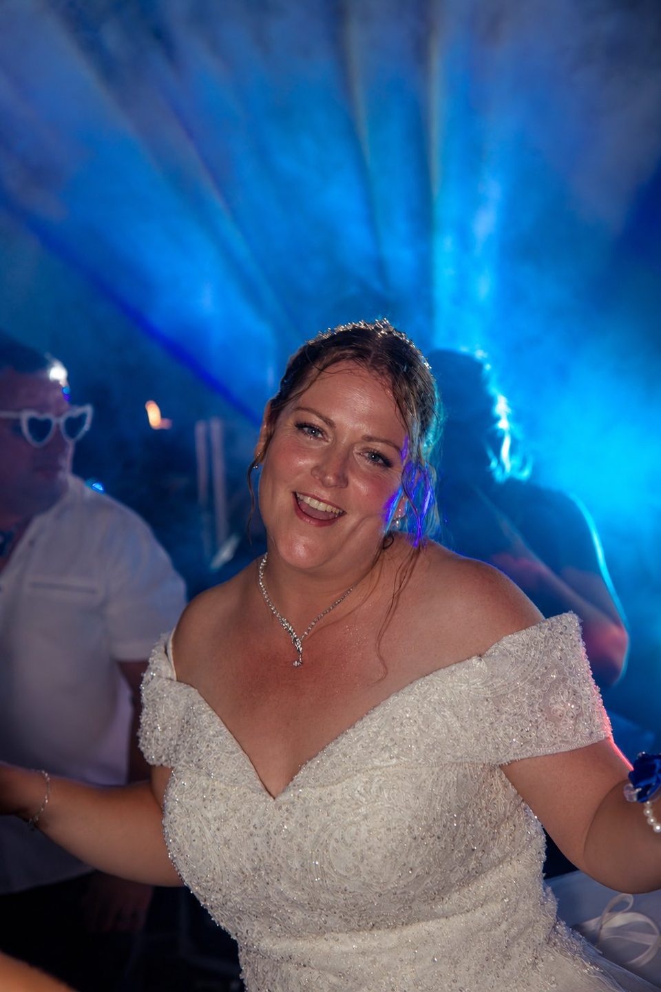 La mariée danse et sourit sous les lumières bleues